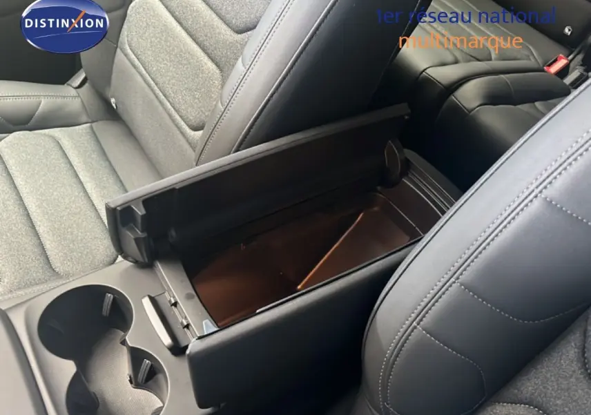 Gros plan intérieur sur la console centrale ouverte et les sièges tissu et cuir noir du Citroën C5 Aircross 2025 hybride.