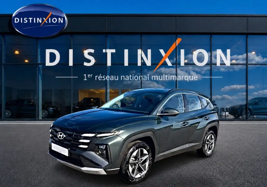 Hyundai Tucson 1.6 t-gdi 239 hybride vert en 3/4 avant droit devant un showroom Distinxion.