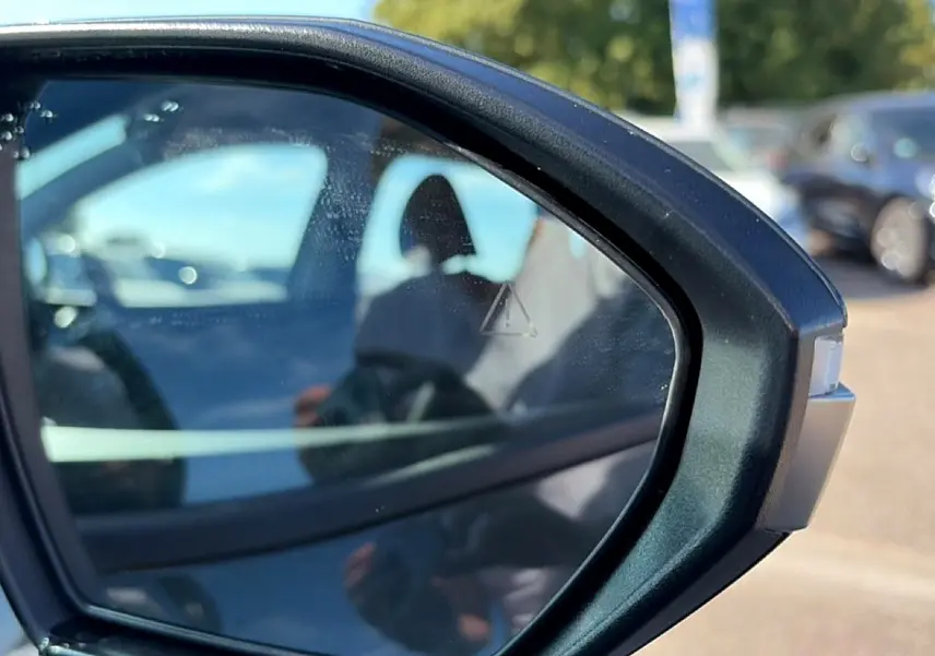 Rétroviseur extérieur droit du Hyundai Tucson vert hybride 2026 avec alerte d’angle mort visible.