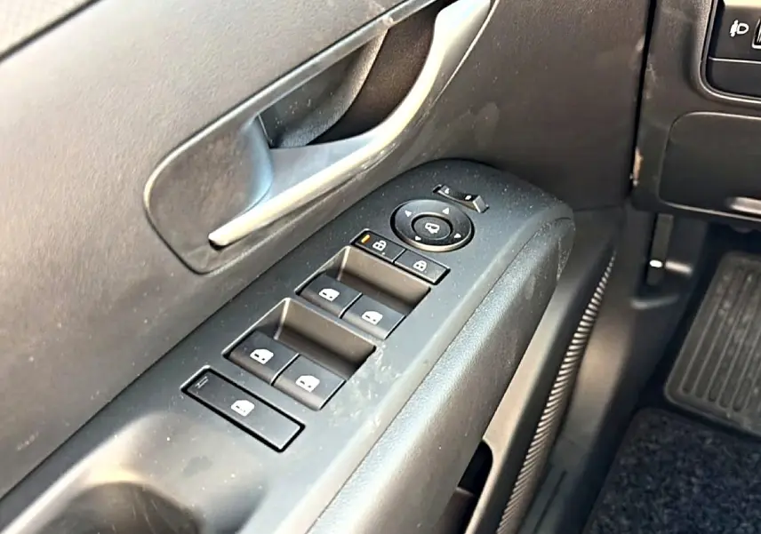 Détail des commandes de vitres et rétroviseurs côté conducteur du Hyundai Tucson 2026 intérieur noir.