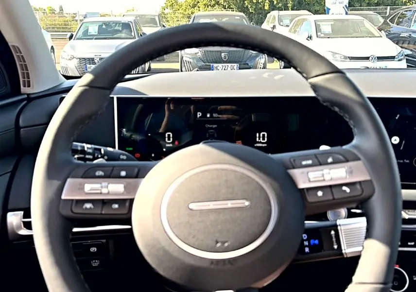 Vue intérieure centrée sur le volant cuir noir multifonction du Hyundai Tucson vert, avec tableau de bord digital en arrière-plan.