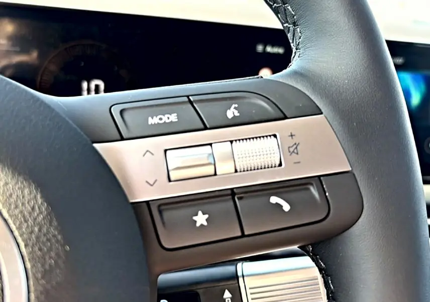 Gros plan sur les commandes audio au volant cuir noir du Hyundai Tucson 2026 hybride, avec molette de volume argentée.