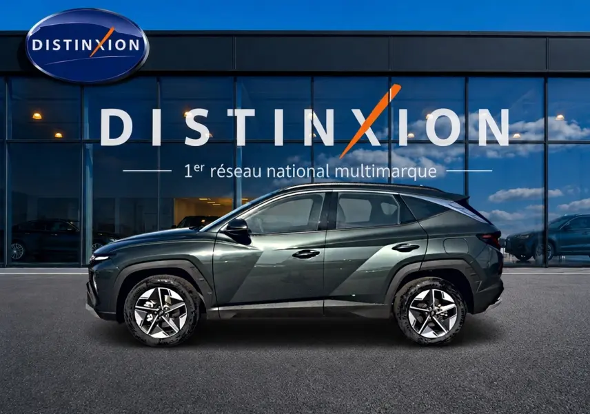 Vue latérale gauche du Hyundai Tucson 2026 vert métallisé avec jantes alliage 18 pouces devant une vitrine Distinxion.