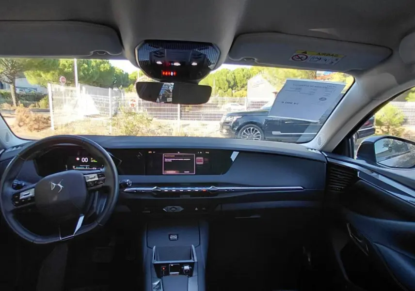 Vue intérieure avant du DS4 Hybride E-Tense 225 gris, mettant en valeur le tableau de bord digital et le volant compact.