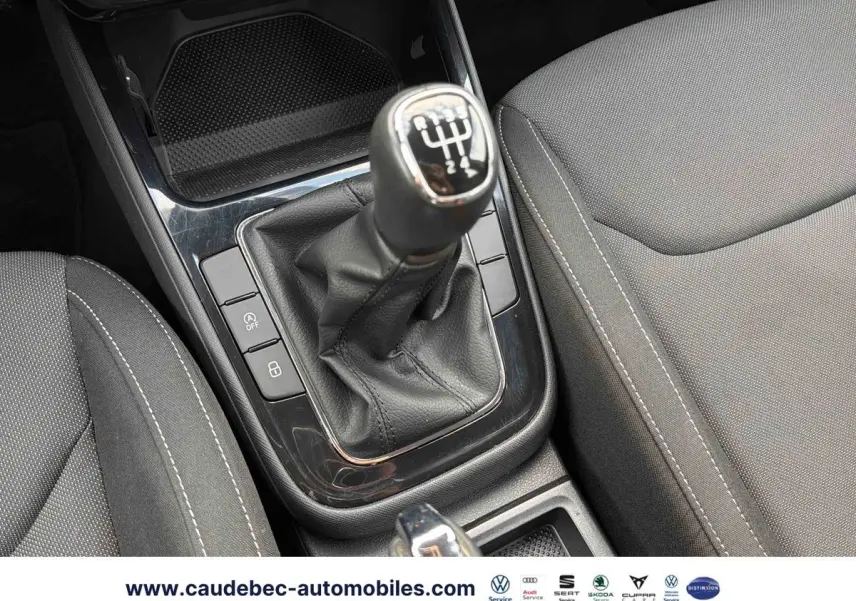 Gros plan sur la commande de boîte manuelle noire et les sièges tissu gris de la Skoda Fabia 2025.