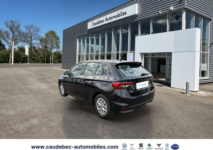Vue 3/4 arrière droite d'une Skoda Fabia noire stationnée devant un bâtiment commercial moderne.