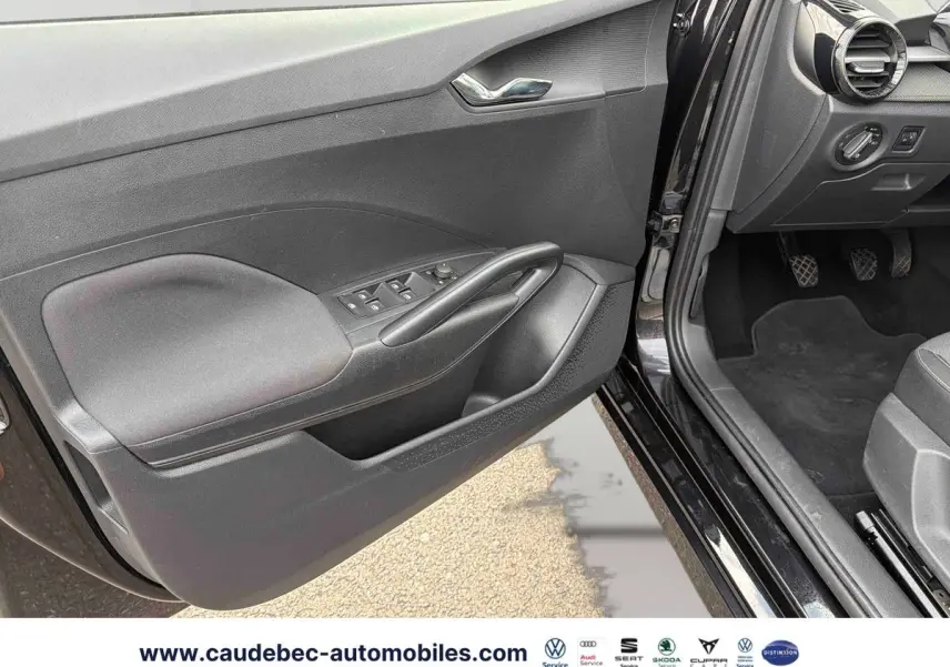 Vue intérieure côté conducteur de la porte noire ouverte d’une Skoda Fabia 2025 avec commandes des vitres et rétroviseurs.