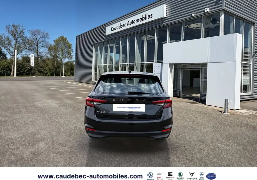 Vue arrière d'une Skoda Fabia noire 2025 stationnée devant un bâtiment moderne avec enseigne Caudebec Automobiles.