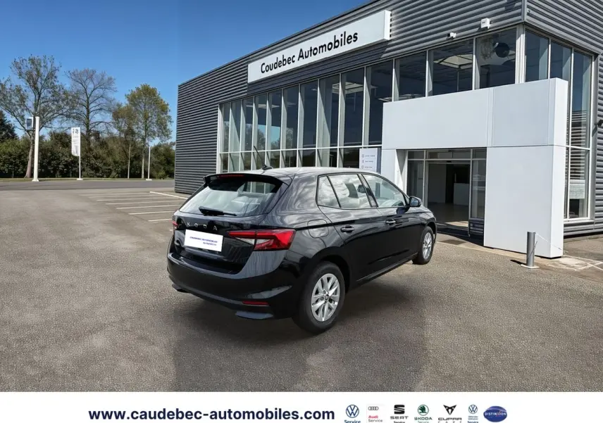 Vue 3/4 arrière droite d'une SKODA Fabia noire stationnée devant un bâtiment moderne de concession automobile.