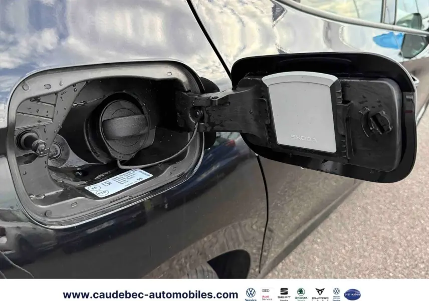 Trappe de carburant ouverte côté gauche d'une Skoda Fabia noire, bouchon essence visible avec logo Skoda.