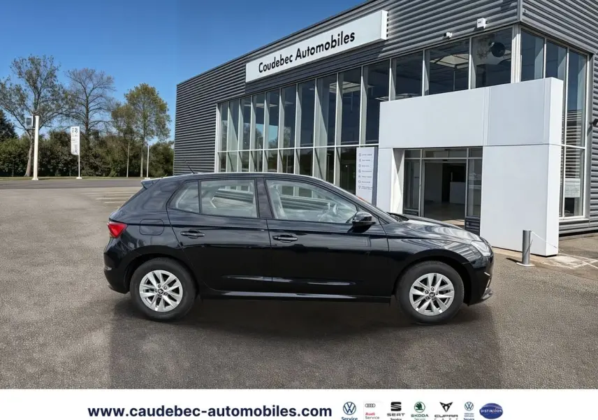 Vue de profil côté gauche d'une Skoda Fabia noire 2025 garée devant un bâtiment moderne de concession.