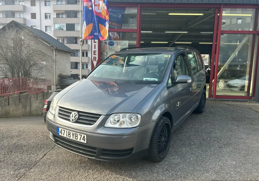 Volkswagen Touran gris 2004 en 3/4 avant droit, avec jantes noires et calandre distinctive Volkswagen.
