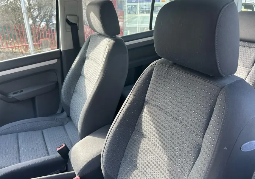 Gros plan sur les sièges avant gris du Volkswagen Touran 2004, montrant le tissu texturé et l'appuie-tête.