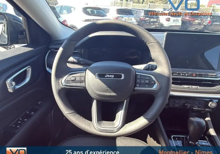 Vue intérieure centrée sur le volant Jeep Compass gris 2023 avec tableau de bord et écran tactile visible.