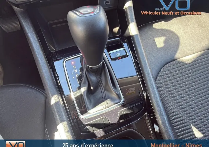 Gros plan sur la console centrale du Jeep Compass gris 2023, mettant en valeur le levier de vitesses automatique et l'accoudoir central.