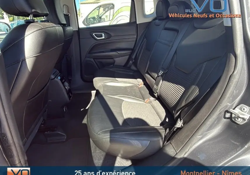 Vue intérieure arrière droite du Jeep Compass gris 2023 montrant les sièges arrière en cuir et tissu avec accoudoir central.