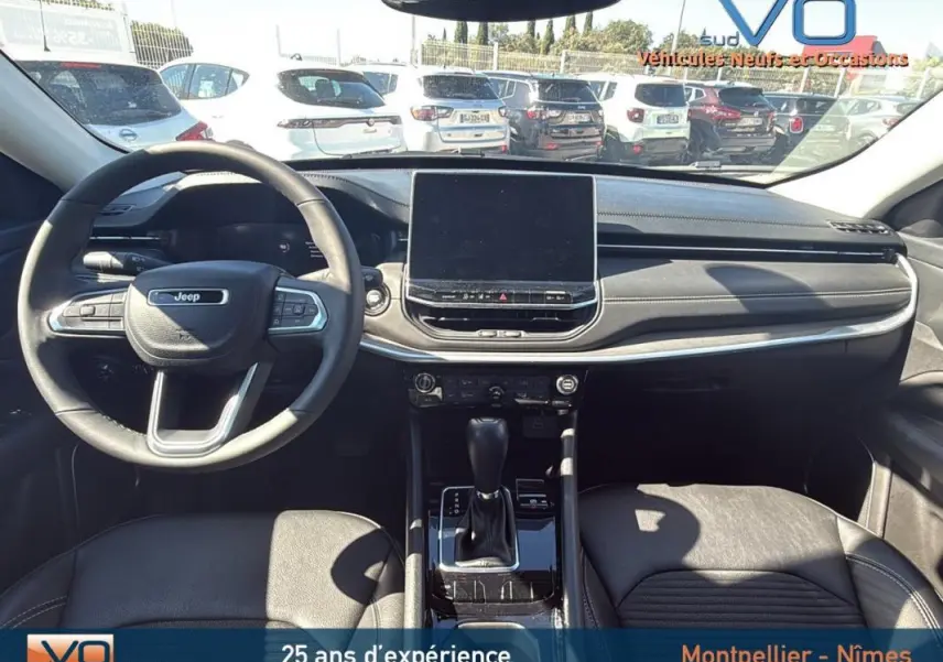 Intérieur du Jeep Compass 2023 vu de face, tableau de bord noir avec écran tactile central et volant multifonction.