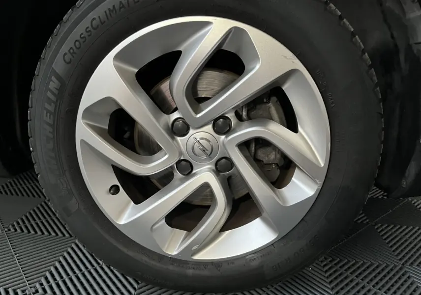 Gros plan sur la jante alliage argentée avec logo Opel au centre, montée sur pneu Michelin CrossClimate.