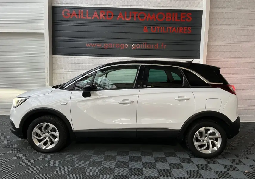 Opel Crossland X blanc vue de profil côté gauche, toit noir contrastant et jantes alliage visibles.