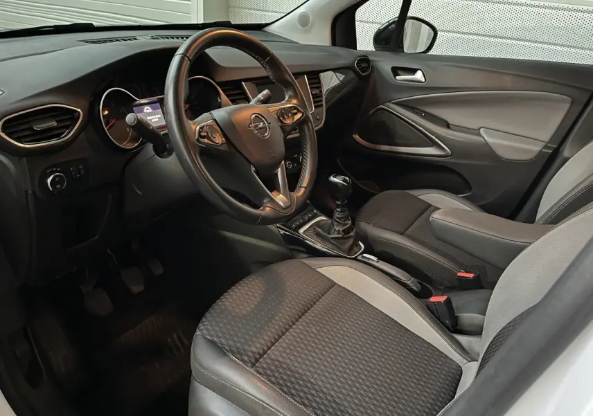 Intérieur avant droit de l’Opel Crossland X blanc, volant cuir, boîte manuelle et sièges tissu bicolores.