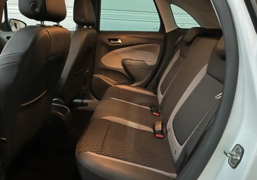 Vue intérieure arrière côté droit de l’Opel Crossland X blanc, montrant la banquette bicolore noire et grise avec appuie-têtes.