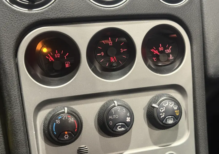 Gros plan sur les commandes de climatisation et les jauges du tableau de bord de l'Alfa Romeo Spider bleu cabriolet 2006.