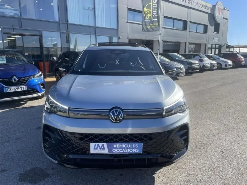 Vue de face du Volkswagen Tiguan 1.5 eHybrid gris métal, version R-line, avec calandre noire et logo central visible.