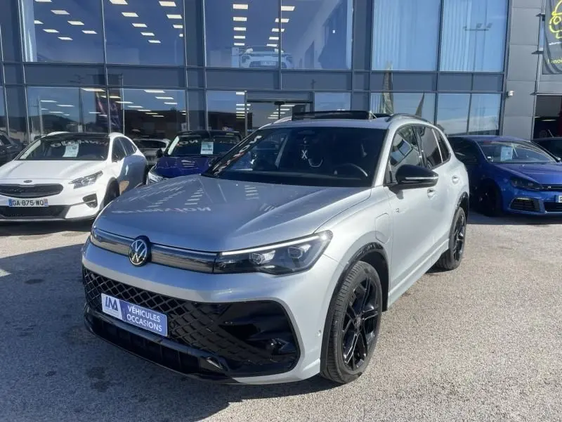 Volkswagen Tiguan 1.5 eHybrid gris métal en 3/4 avant droit, avec jantes noires et toit ouvrant panoramique.