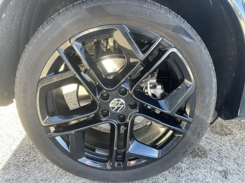 Gros plan sur la jante noire brillante du Volkswagen Tiguan 1.5 eHybrid R-line 2025 en gris métal.