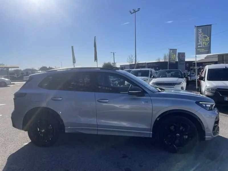 Vue de profil côté gauche d'un Volkswagen Tiguan 1.5 eHybrid gris métal avec jantes noires et finition R-line.