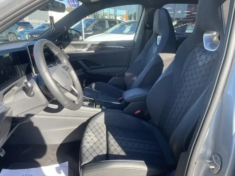 Vue intérieure côté conducteur du Volkswagen Tiguan 1.5 eHybrid 2025, sièges R-line en tissu gris à motifs losanges.