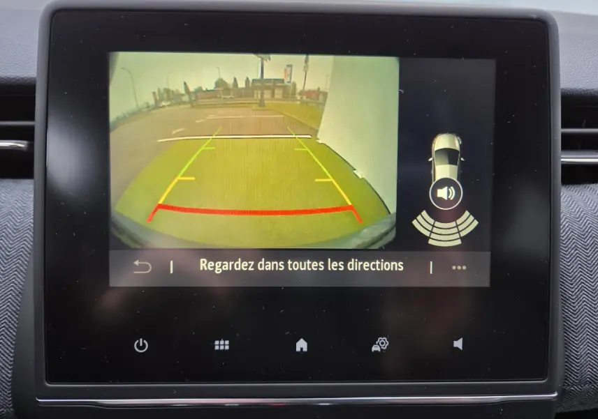 Écran multimédia montrant la caméra de recul de la Renault Clio gris schiste, avec guidage de trajectoire coloré.