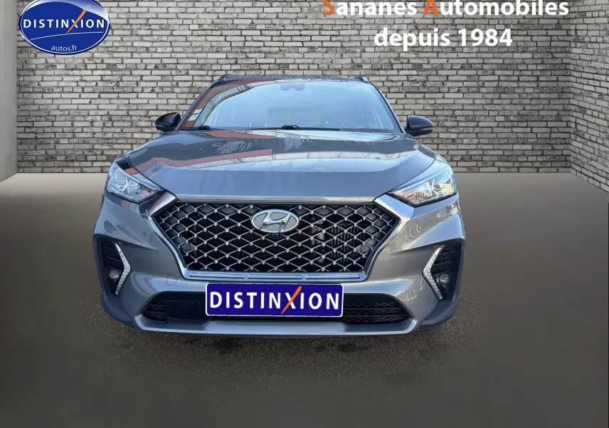 Vue frontale d'un Hyundai Tucson 1.6 Hybrid gris foncé avec calandre large et phares LED distinctifs.