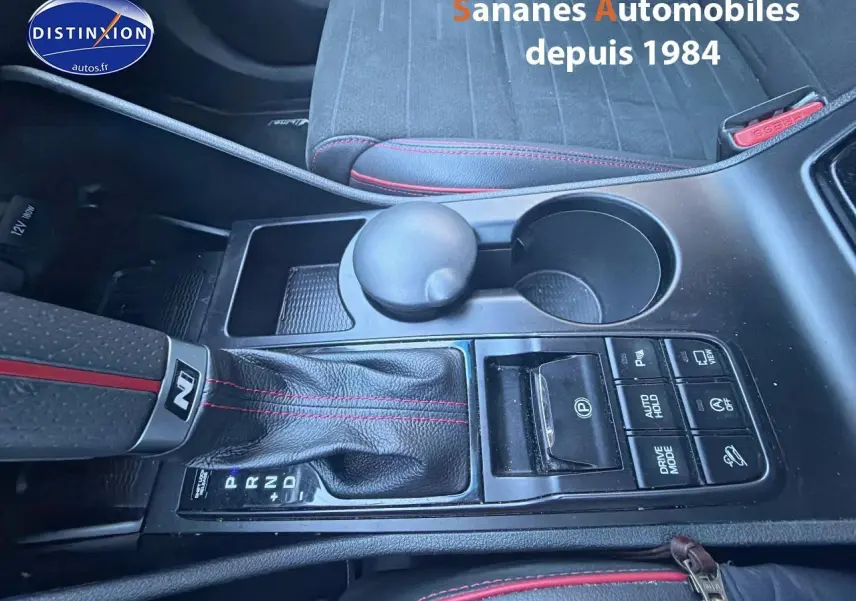 Vue rapprochée de la console centrale du Hyundai Tucson N Line 1.6 Hybrid, cuir noir avec surpiqûres rouges.