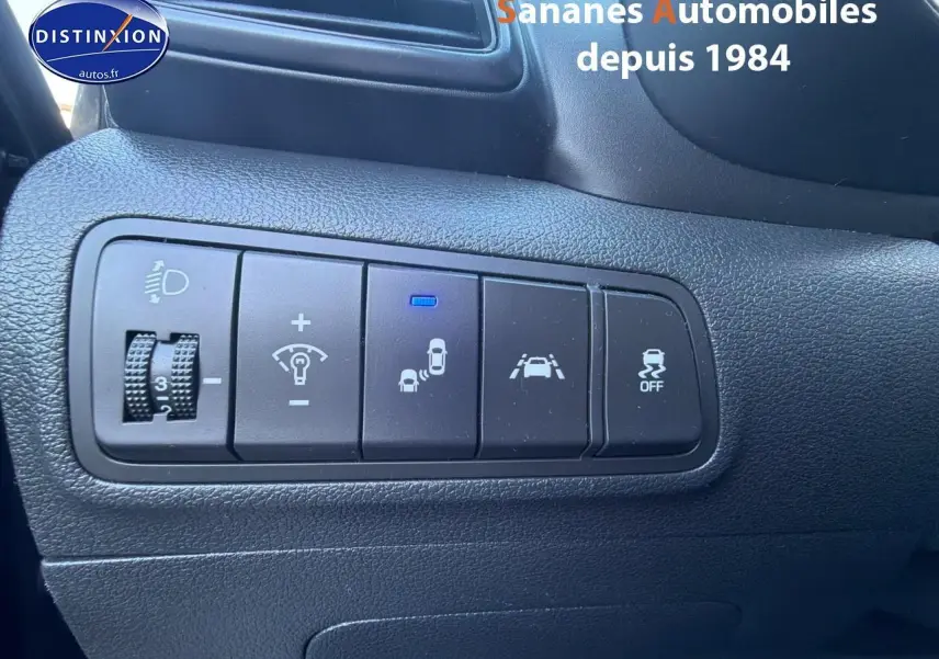 Vue rapprochée des commandes de sécurité et d’éclairage sur tableau de bord noir d’un Hyundai Tucson gris foncé.