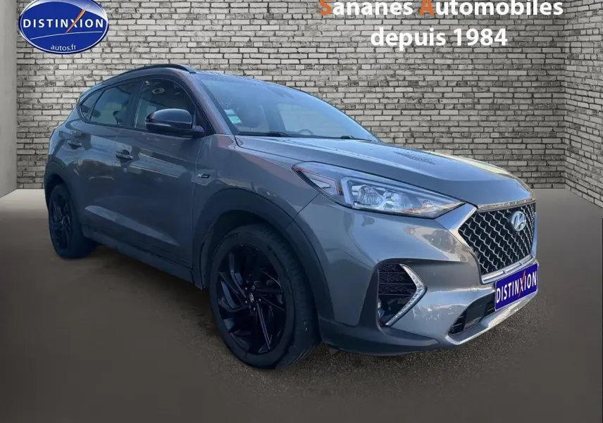 Vue 3/4 avant gauche d'un Hyundai Tucson 1.6 Hybrid 136 N Line gris foncé avec jantes alliage noires.