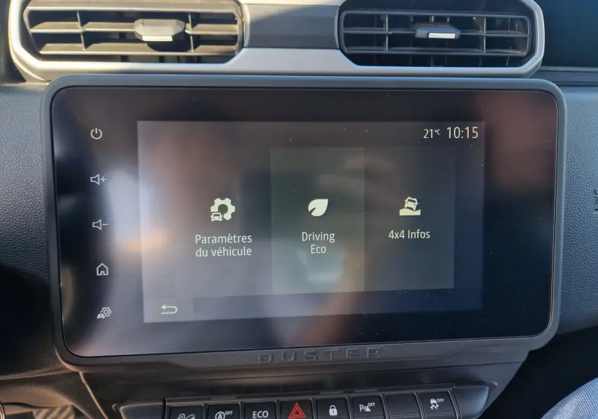 Écran tactile central du Dacia Duster 2024 blanc, affichant les paramètres véhicule et options 4x4, vue intérieure frontale.