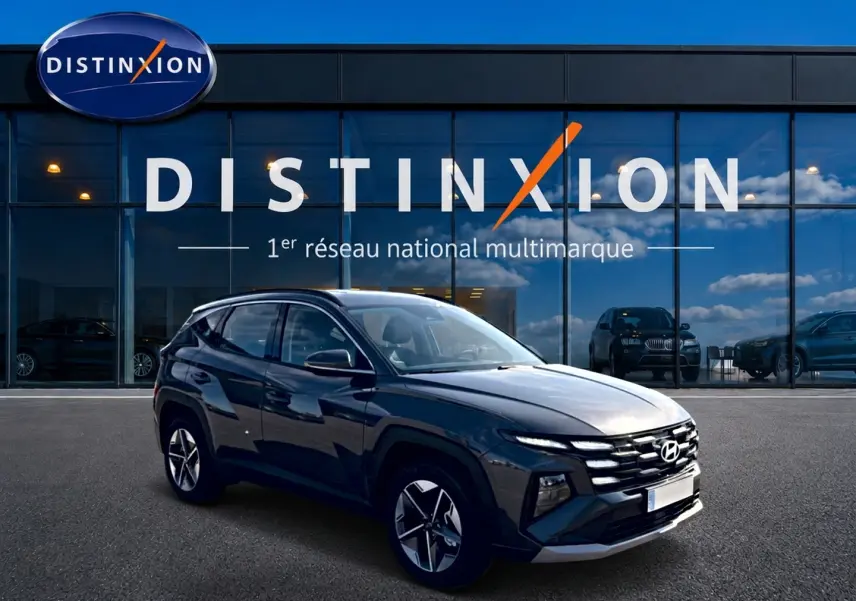 Hyundai Tucson gris ecotronic en 3/4 avant droit, avec jantes alu et calandre distinctive, devant showroom Distinxion.