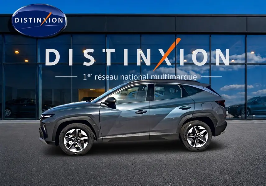 Vue de profil côté gauche d'un Hyundai Tucson gris ecotronic devant une vitrine avec logo Distinxion.