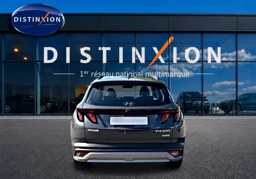 Vue arrière d'un Hyundai Tucson gris ecotronic 2026 hybride garé devant une vitrine avec logo Distinxion.