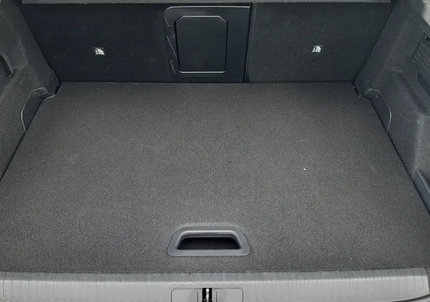 Vue plongeante sur le coffre spacieux et propre d’une Citroën C4 gris 2024, avec plancher plat et trappe arrière.