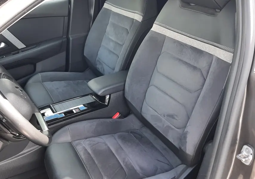 Vue intérieure côté conducteur de la Citroën C4 2024, sièges en tissu et cuir gris avec surpiqûres contrastées.