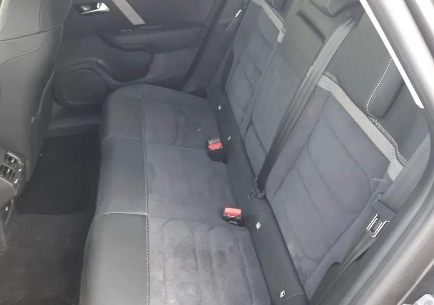 Vue intérieure côté droit des sièges arrière en tissu et cuir noir du Citroën C4 2024 gris, avec ceintures de sécurité visibles.