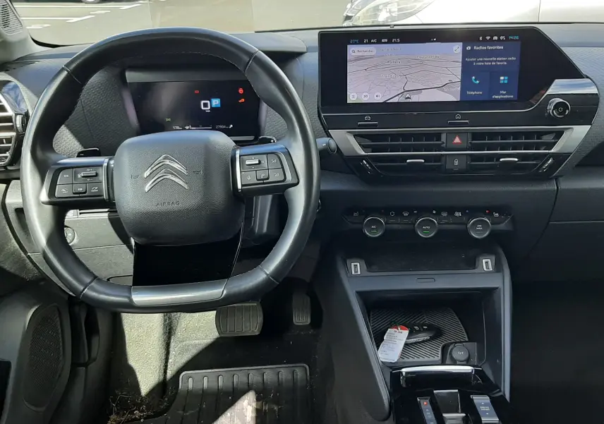 Intérieur noir de Citroën C4 2024, vue frontale du volant et tableau de bord avec écran tactile central allumé.