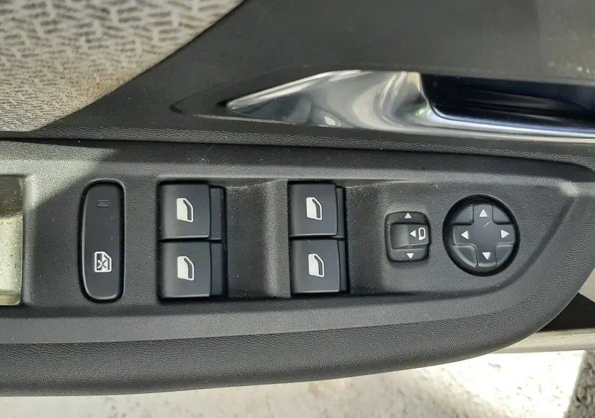 Panneau de commandes des vitres et rétroviseurs côté gauche intérieur d'une Citroën C4 gris 2024.