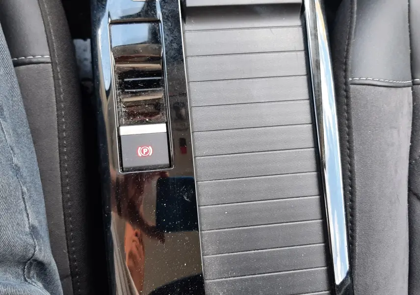 Vue rapprochée de la console centrale noire avec frein à main électronique sur Citroën C4 gris 2024.