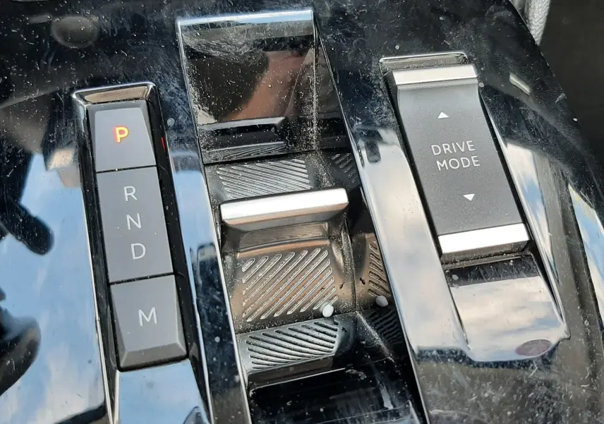 Gros plan sur la console centrale noire brillante de la Citroën C4 1.2 PureTech 130ch avec sélecteur de boîte auto et bouton Drive Mode.