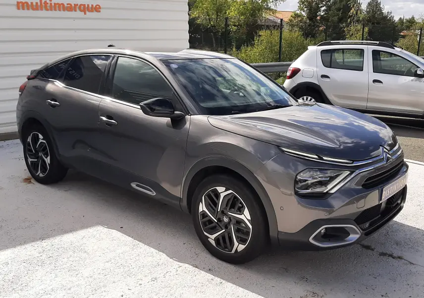Citroën C4 gris 2024 vue 3/4 avant droit, avec jantes bi-ton et phares LED distinctifs.