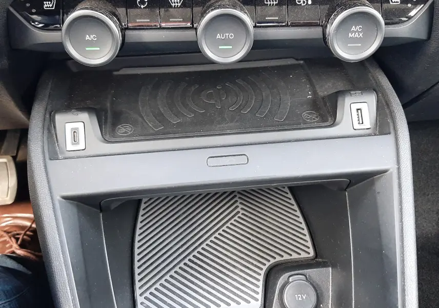Vue rapprochée de la console centrale noire de la Citroën C4 2024, avec commandes climatisation et chargeur sans fil.
