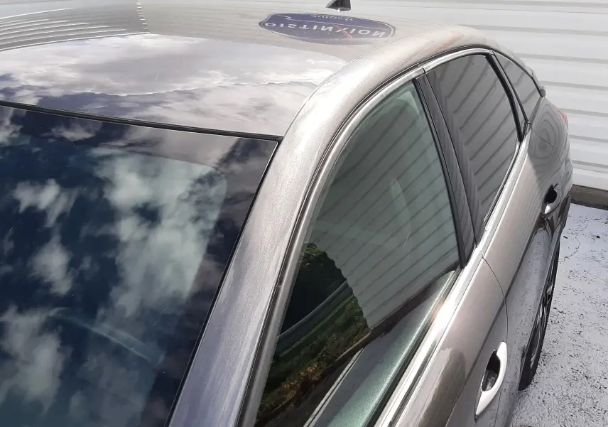 Vue en plongée côté gauche arrière d'une Citroën C4 gris métallisé avec toit panoramique et vitres teintées.